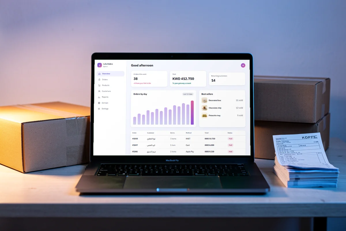 A laptop among parcels showing the store dashboard: orders by day, best sellers and paid orders.